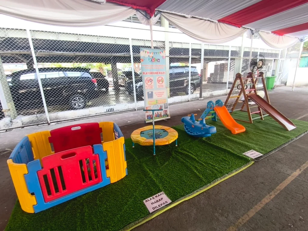 Trampolin, perosotan, dan playpen Baby Adha terpasang di area outdoor untuk acara